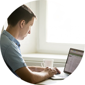 Man in white shirt sitting at a desk looking at a computer screen