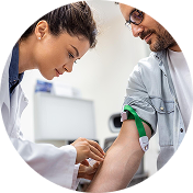 Female medical provider in a white coat drawing blood from a male patient's arm